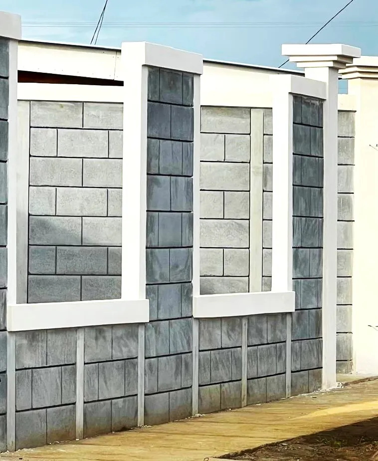 Diseño arquitectónico de muro frontal elegante utilizando el sistema Maxiblock. Combina bloques prefabricados expuestos con marcos estructurales blancos texturizados que crean aperturas decorativas, complementado con una columna principal estilizada para portón.
