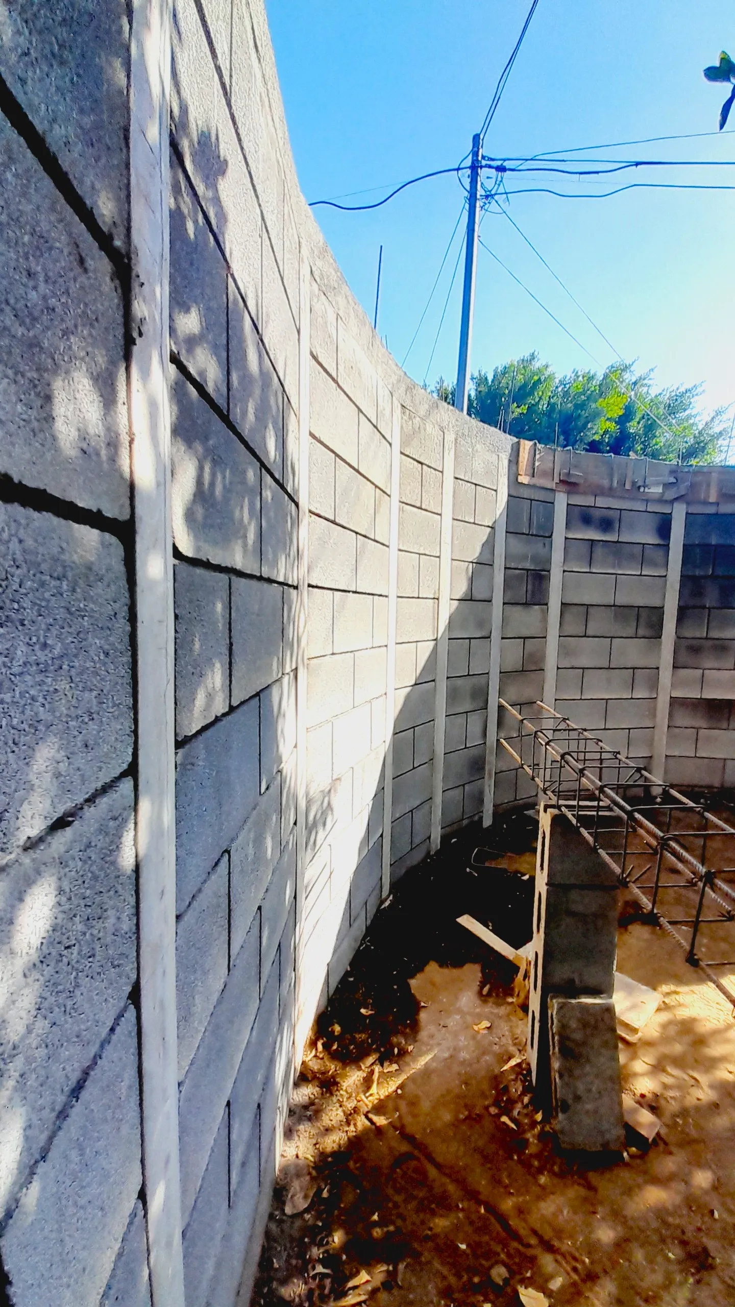 Vista en detalle del proceso de construcción de un muro perimetral curvo con bloques prefabricados del sistema Maxiblock, mostrando las columnas de concreto reforzado y la precisión estructural antes de la aplicación de los acabados finales.