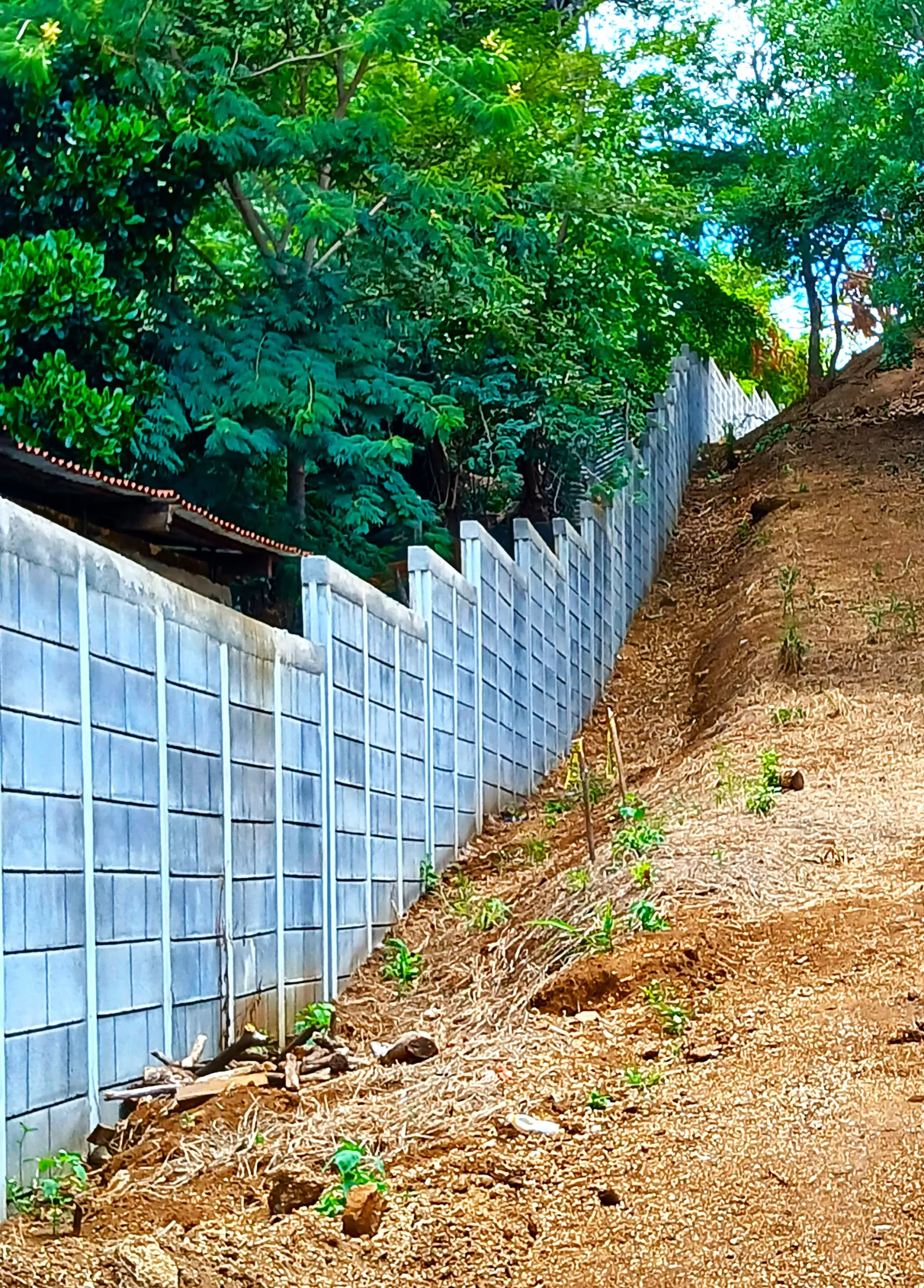Muro de contención y cerramiento perimetral escalonado construido en una pendiente natural utilizando el sistema de bloques prefabricados Maxiblock, ideal para adaptarse a la topografía de cualquier terreno con alta resistencia.