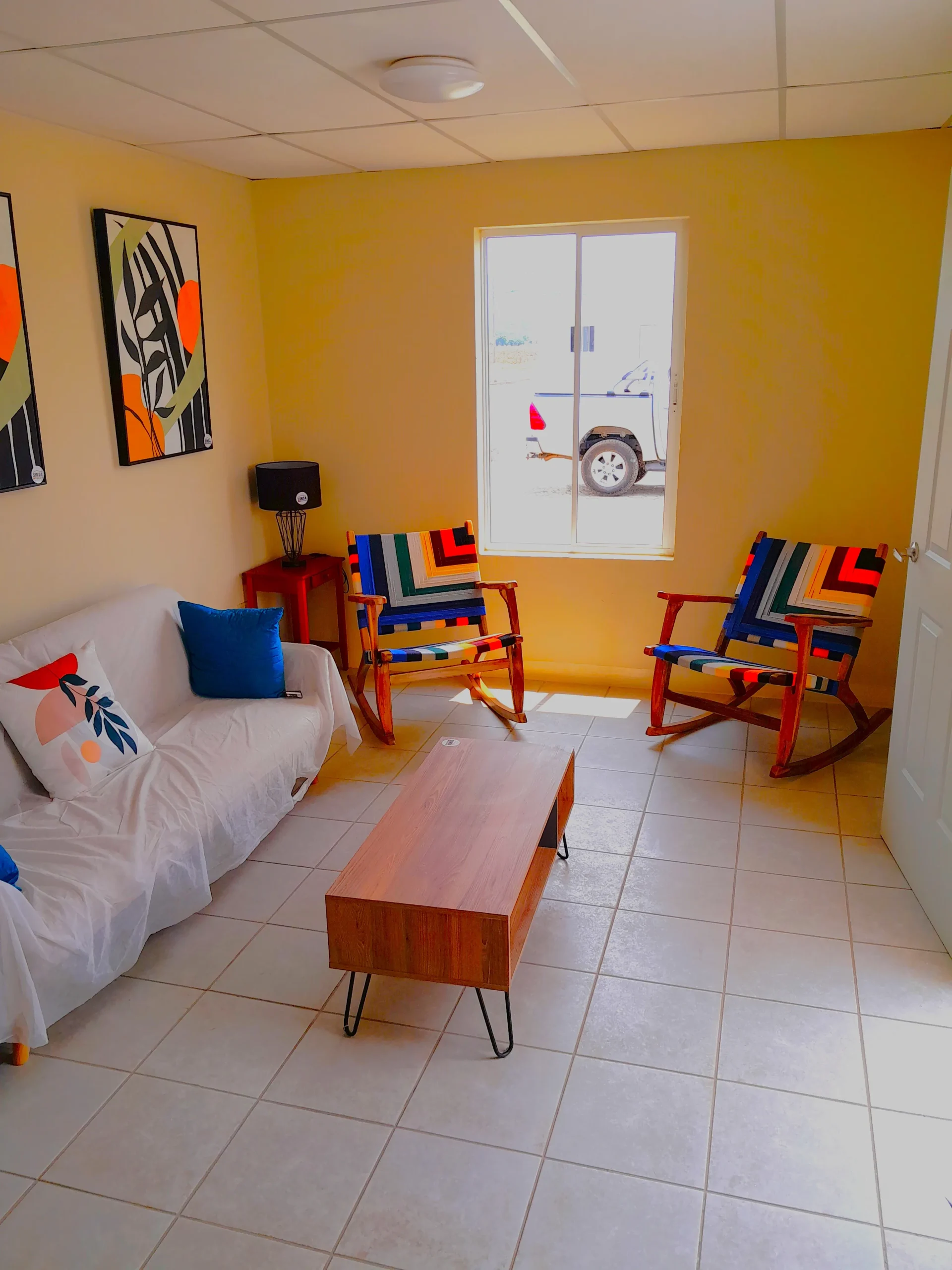 Sala de estar acogedora en viviendas prefabricadas nicaragua. Piso cerámico, ventanas de aluminio y muebles con decoración moderna.