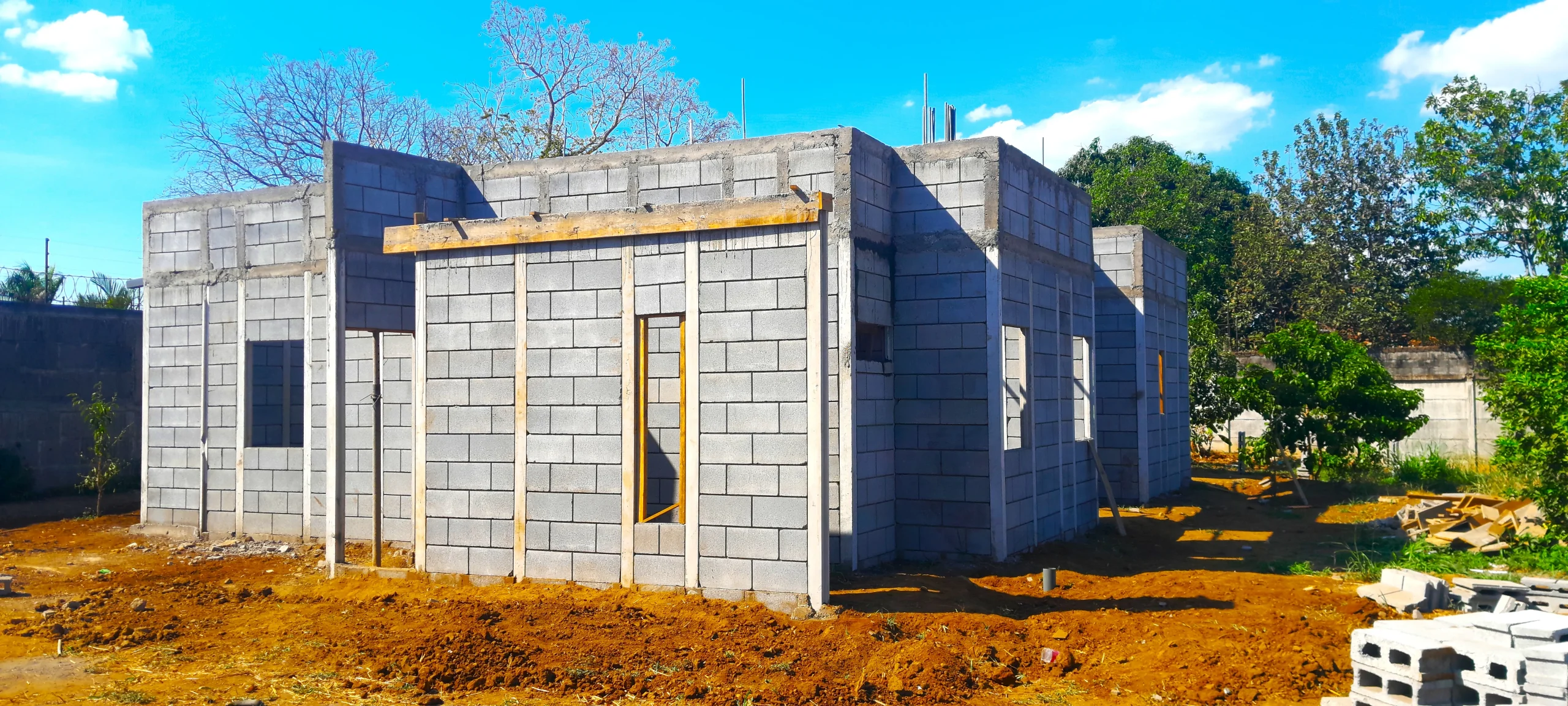 Vista exterior de viviendas prefabricadas nicaragua en construcción con Maxiblock. Paredes modulares grises y columnas integradas en el terreno.