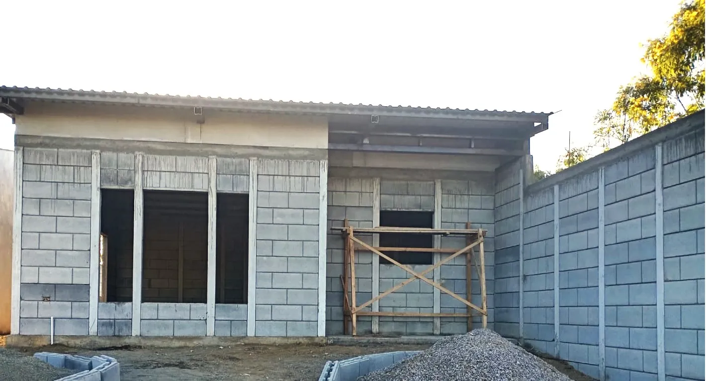 Fachada y muro de viviendas prefabricadas nicaragua en proceso de obra con bloques Maxiblock expuestos y andamios de madera.