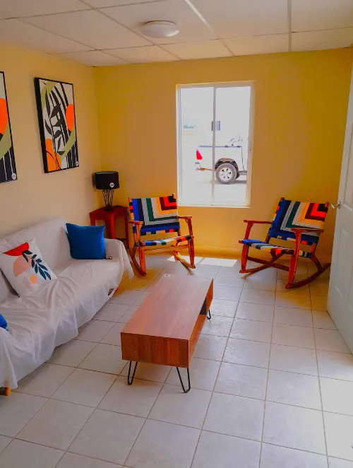 Sala de estar acogedora en viviendas prefabricadas nicaragua. Piso cerámico, ventanas de aluminio y muebles con decoración moderna.