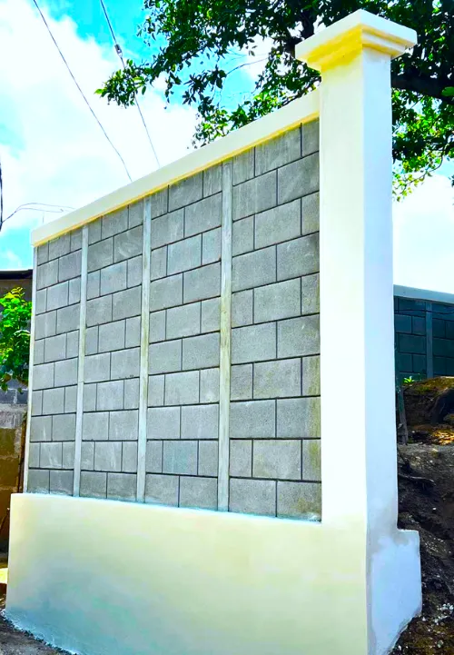 Fachada elegante de muro frontal construido con Maxiblock, zócalo inferior como muro de contención y columnas decorativas estructurales.