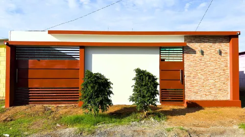 Fachada frontal residencial construida con Sistema Maxiblock de ARCON, acabados decorativos en pintura y columnas estructurales estéticas.