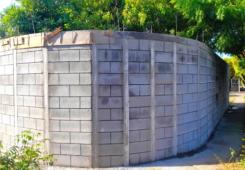 Exterior de un muro curvo de concreto perimetral construido con postes pretensados de 5000 PSI y bloques modulares Maxiblock.